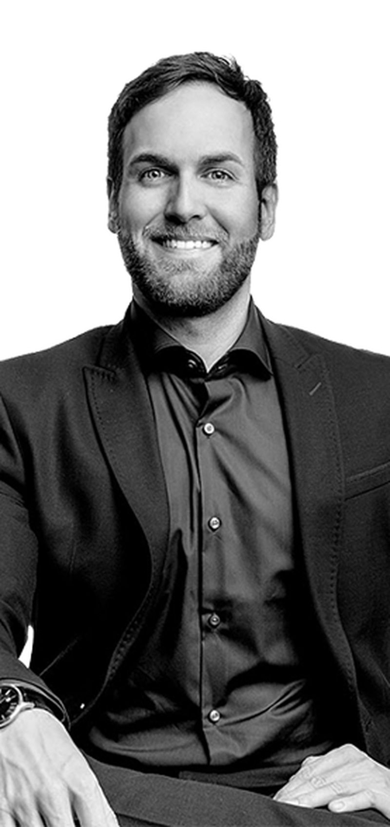 Robert Böck, CEO von Lindermeir + Company, in dunklem Sakko und dunklem Hemd, sitzt vor hellem Hintergrund und lächelt in die Kamera